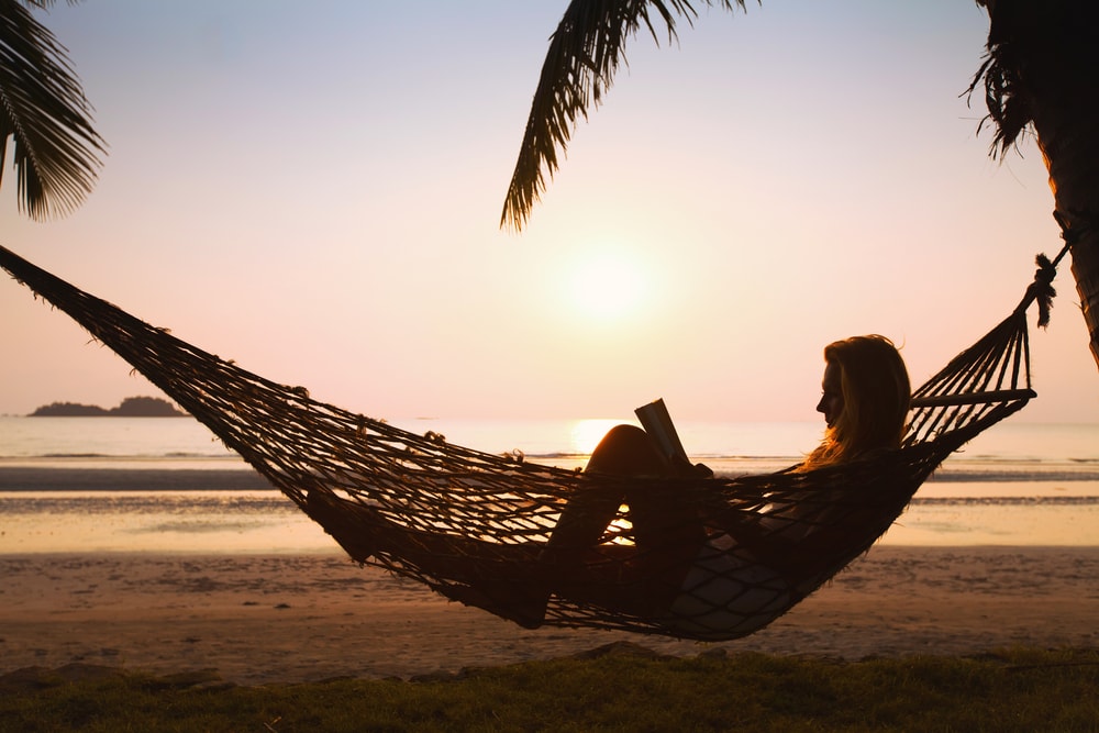silhouette of woman relaxing in hammock on the beach