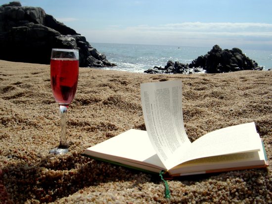 A glass of wine and a book on the beach