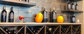 Wine bottles and pumpkins displayed on shelves in a wine shop or tasting room.