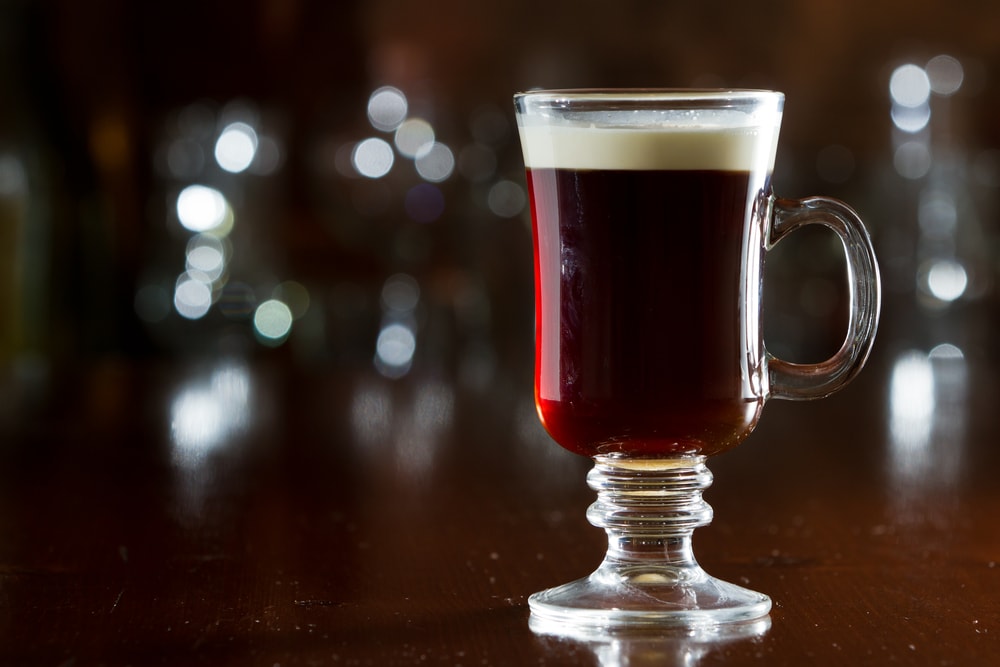 closeup of an irish coffee saved on a dark bar with a float of heavy cream