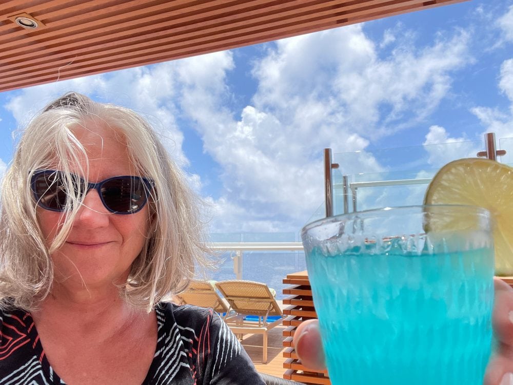 a woman holding a blue tropical drink