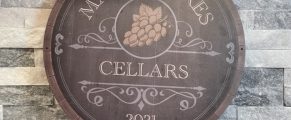A Tasting Guide to Sicilian Wines 1 Wooden sign for Manzanar Cellars winery with grapevine logo, 2021, on stone wall.