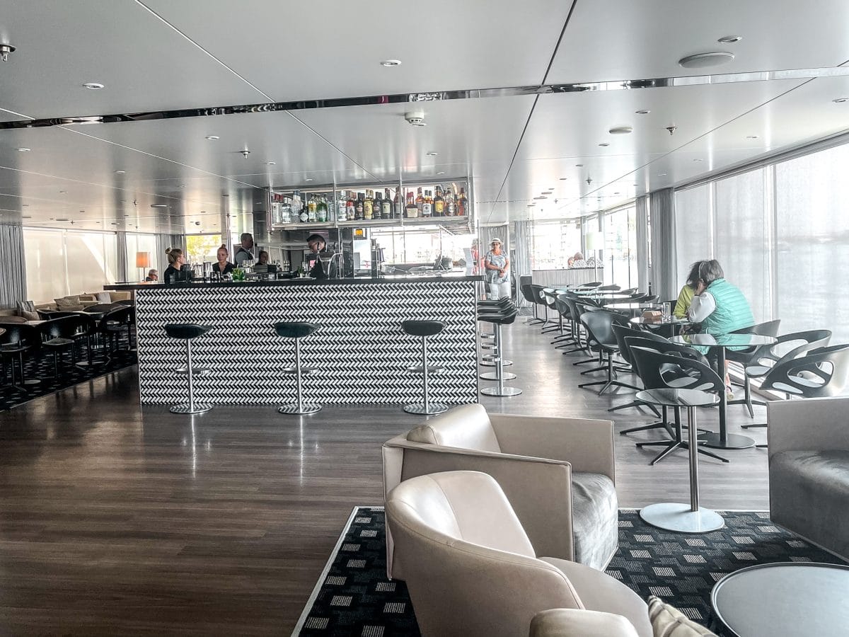Bright lounge on Scenic Crystal river cruise with black and white bar and lots of seating.