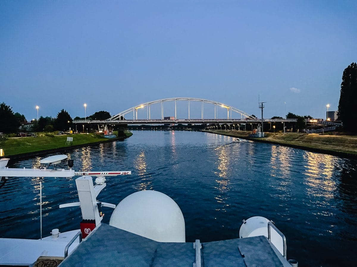 view from top deck of a river cruise ship as it gets ready to pass below a bridge at night