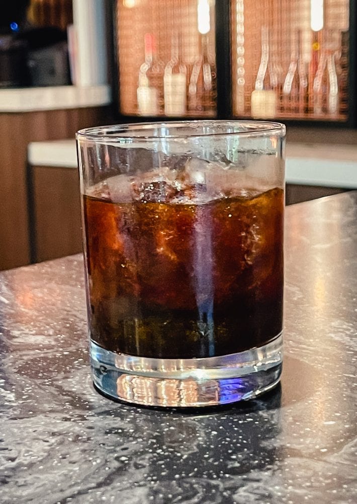 coffee and whisky specialty cocktail in glass sitting on metal table