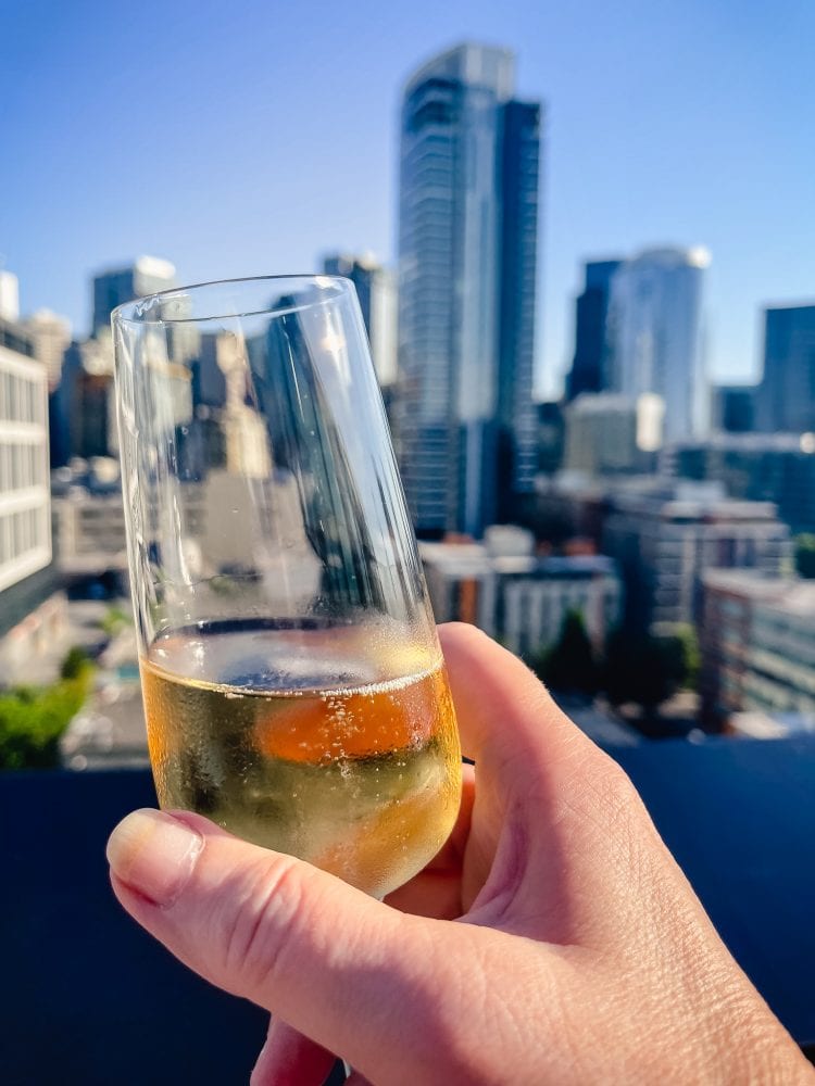 glass of champagne held up in front on the seattle skyline on a sunny day
