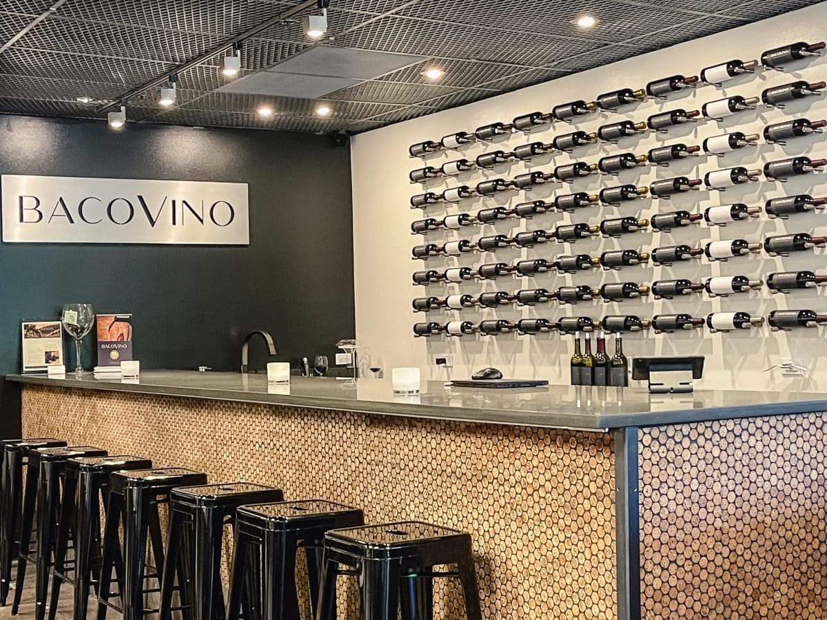 a bar and counter in a wine tasting room with bottles of wine on display in back