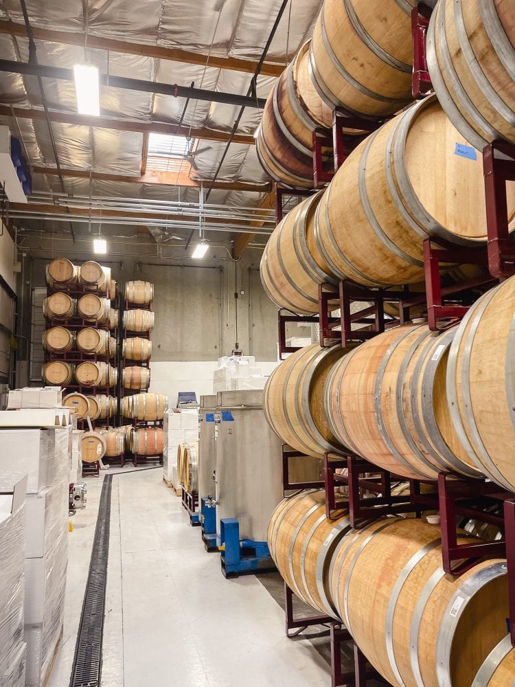 wine production facility at bacovino winery in seattle shows wine barrels, fermenting vats, and boxes ready to ship