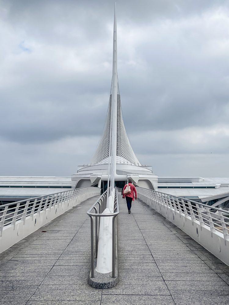 A person walking along the bridge to enter the milwaukee art museum
