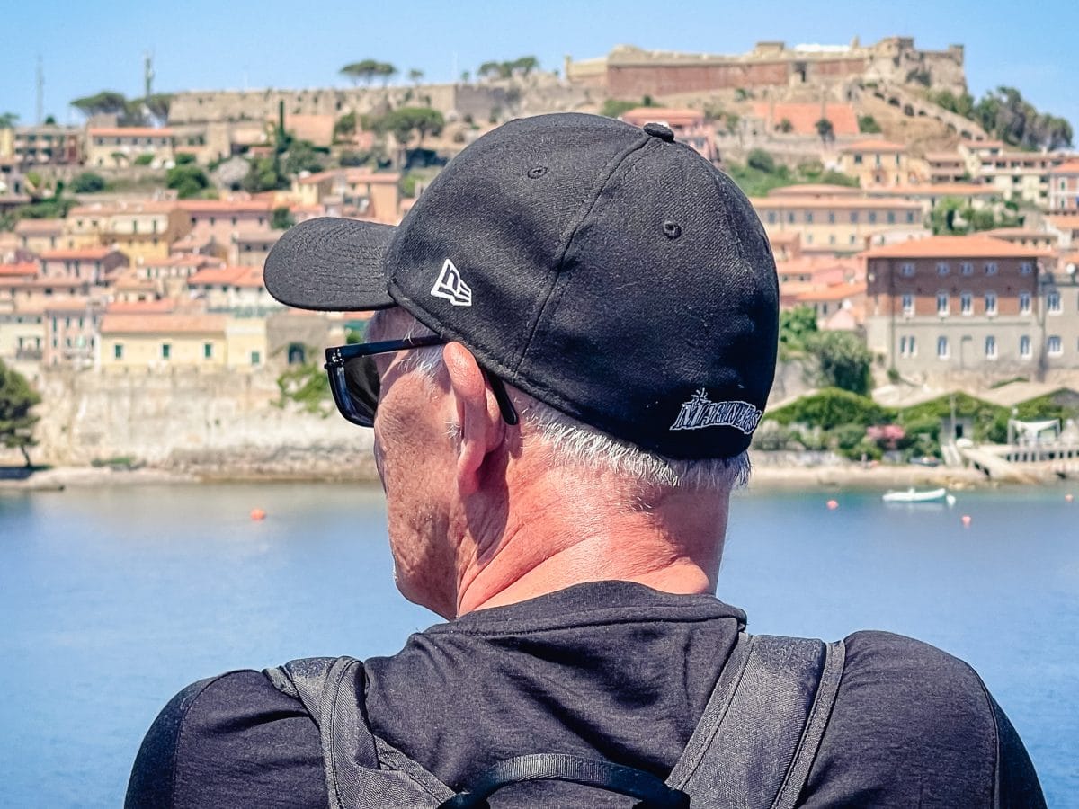 a man looking out at a medieval town from the water