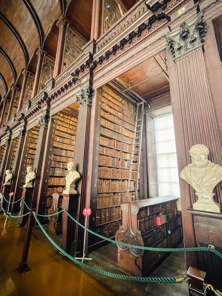 book shelves fronted by marble busts at long room at trinity college in dublin