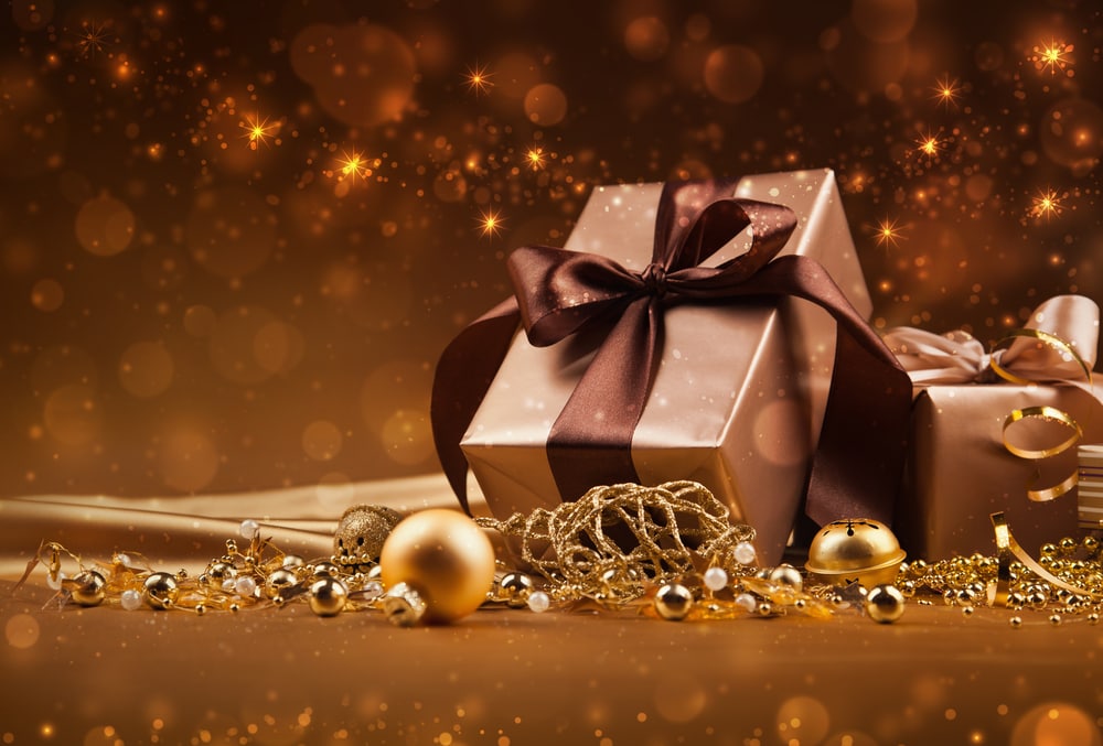 holiday packages beneath a tree with ornaments draped about them