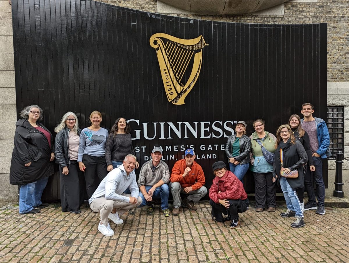 group of people standing in front of a sign at the guinness storehouse in dublin ireland