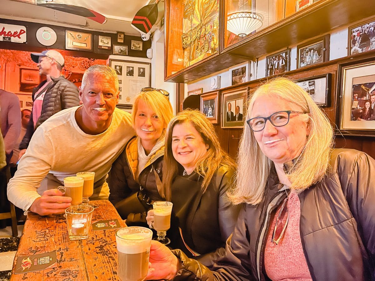 group of people in a bar drinking irish coffees with a cream mustache