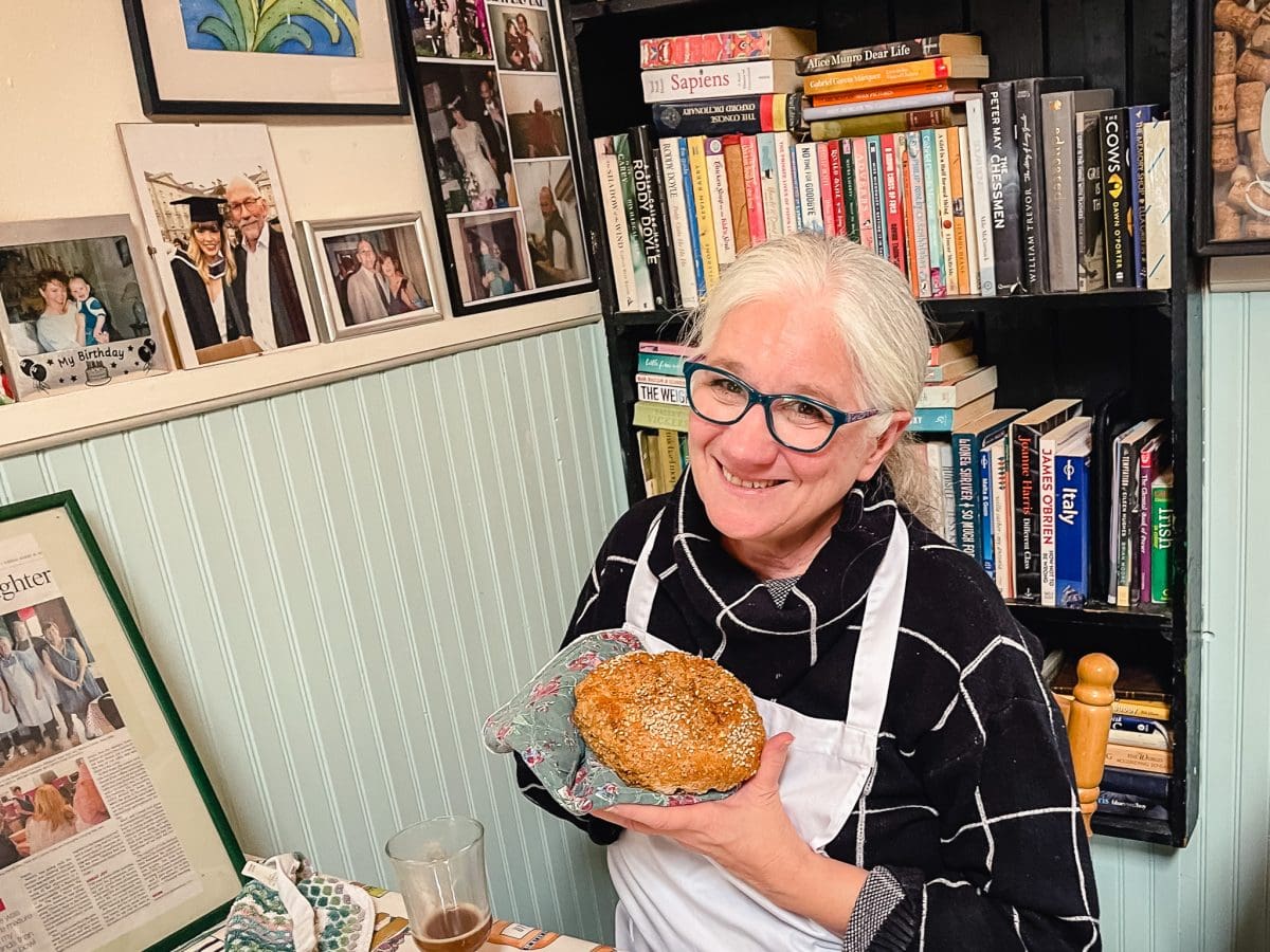 a smiling woman holding a loaf of warm irish soda bread in her hands