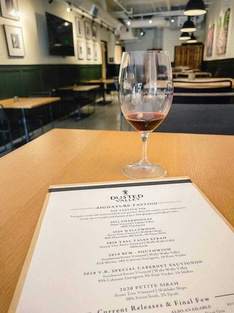 a wine tasting menu with a glass of red wine