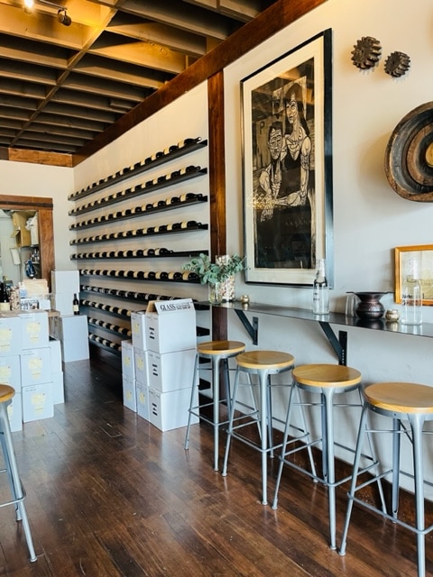 interior of darby winery in west seattle showing bottles of wine on the wall and stools for seating