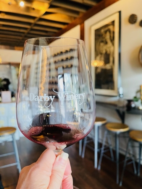 a glass of red wine in a wine glass etched with darby winery