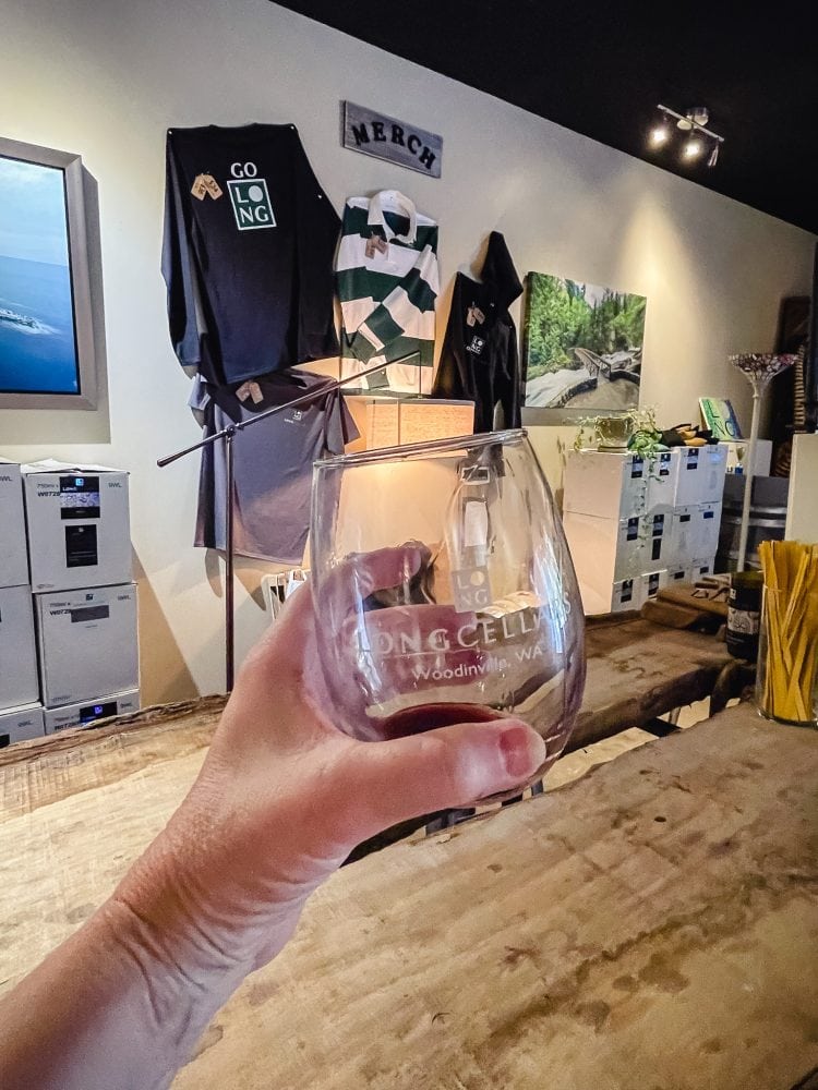 a stemless wine glass with red wine toasting in a tasting room