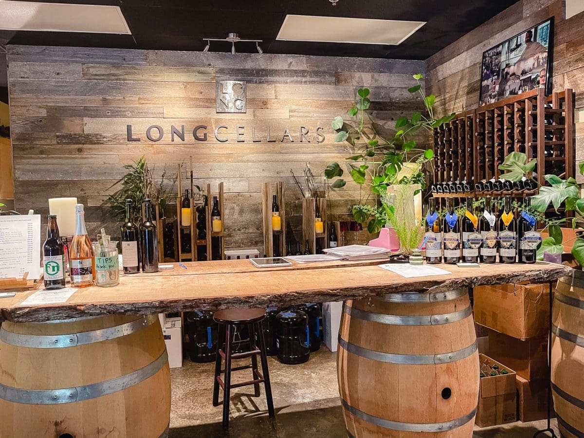 wine tasting room with racks of wine along the wall and a display of various wines to be tasted