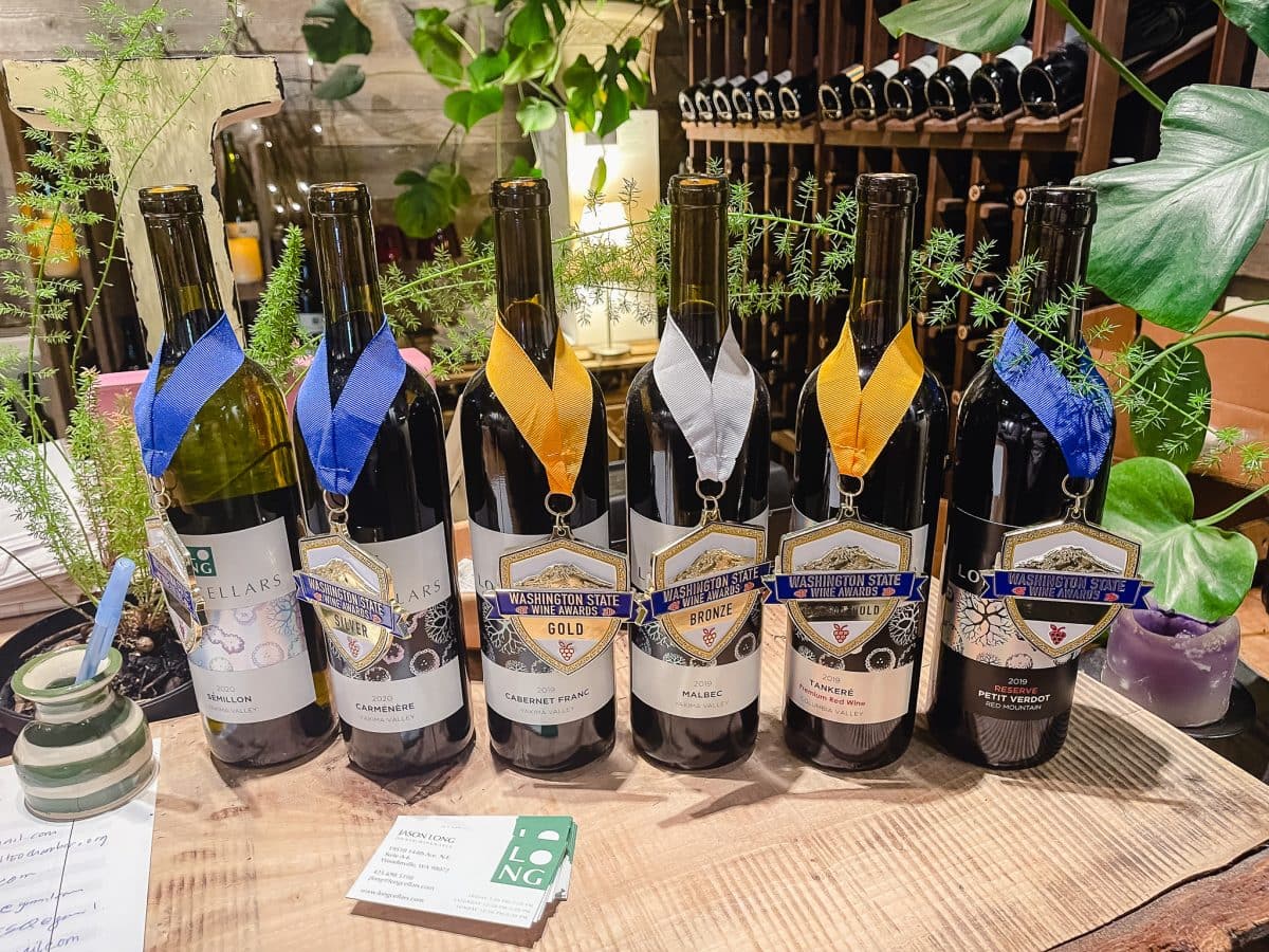 a line up of six bottles of wine draped with award ribbons