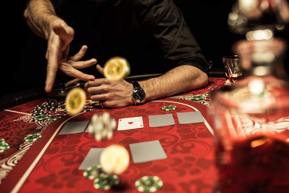 man play9ing cards on red felt gaming table