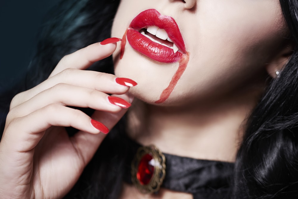 beautiful woman vampire with fangs and blood dripping from mouth