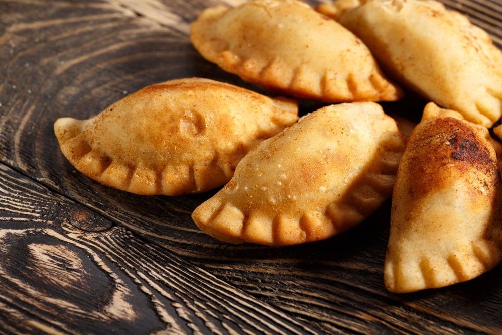 Fried colombian empanadas on wooden table. Savory stuffed patties also known as pastel,pate or pirozhki