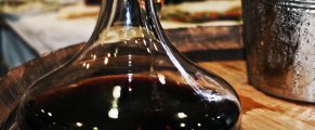 Romanian Wine: A Rich & Resplendent World 6 Rich red wine in a decanter on a rustic wooden table.