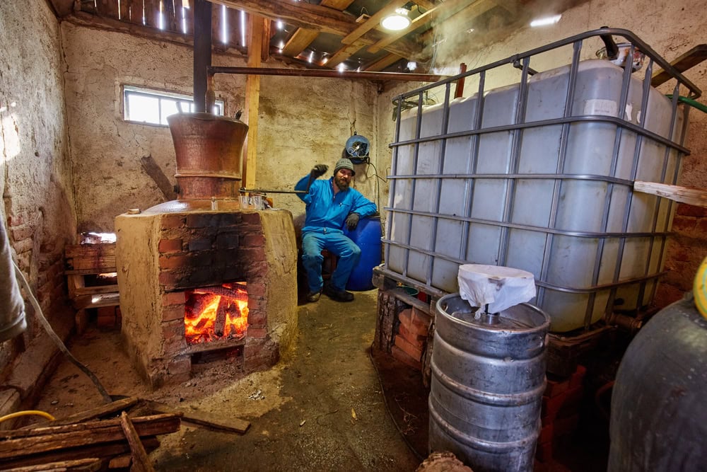 A man in a blue suit is sitting in a room with a wood stove.
