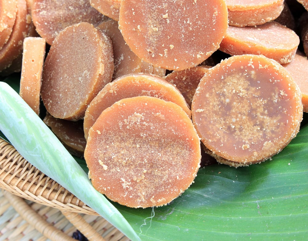 A basket filled with palm sugar disks on top of a green leaf.