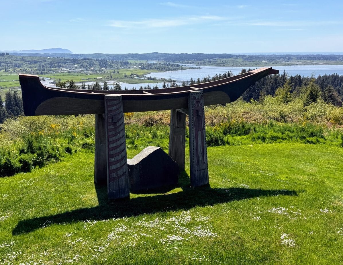 A large wooden sculpture on top of a grassy hill.