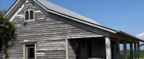 Small Town Weekend Getaway: Sweetwater, Tennessee 16 Rustic wooden farm shed with weathered siding and metal roof under clear blue sky.