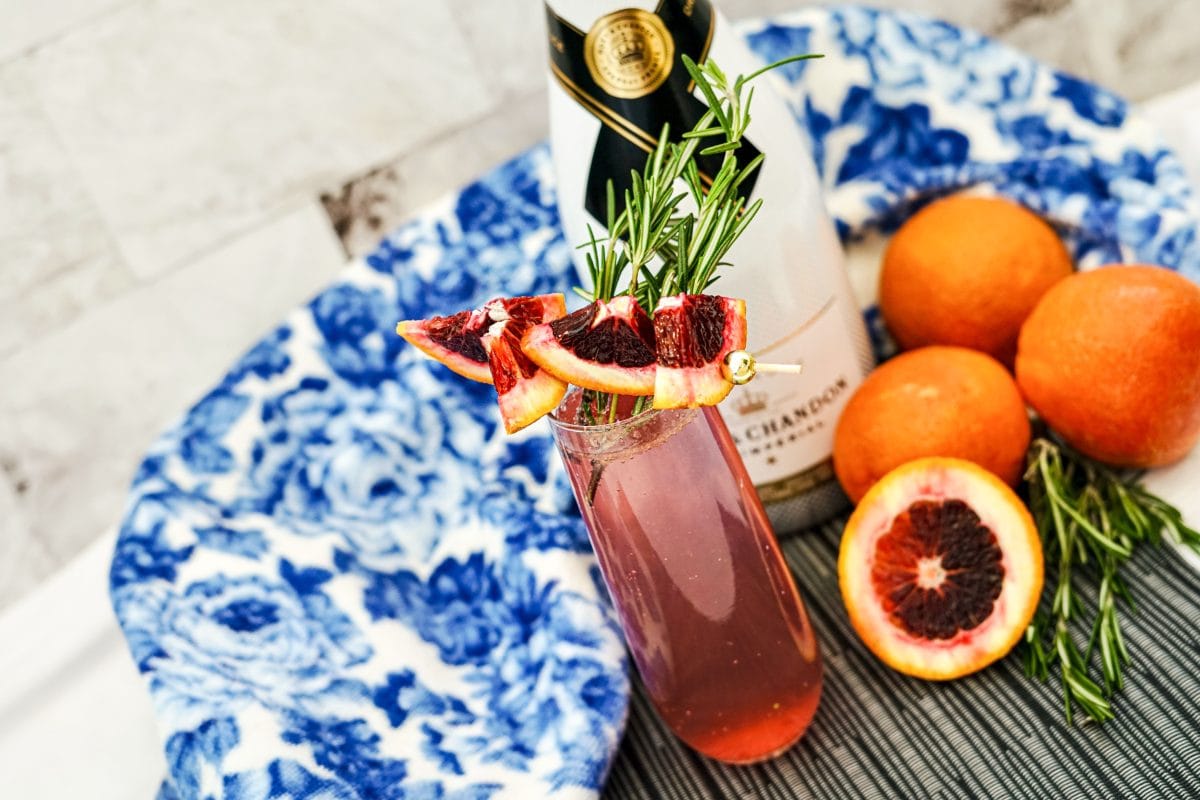 Blood Orange Mimosas: A Refreshing Twist on a Classic 6 Festive presentation on a placemat of blood orange mimosa and ingredients.