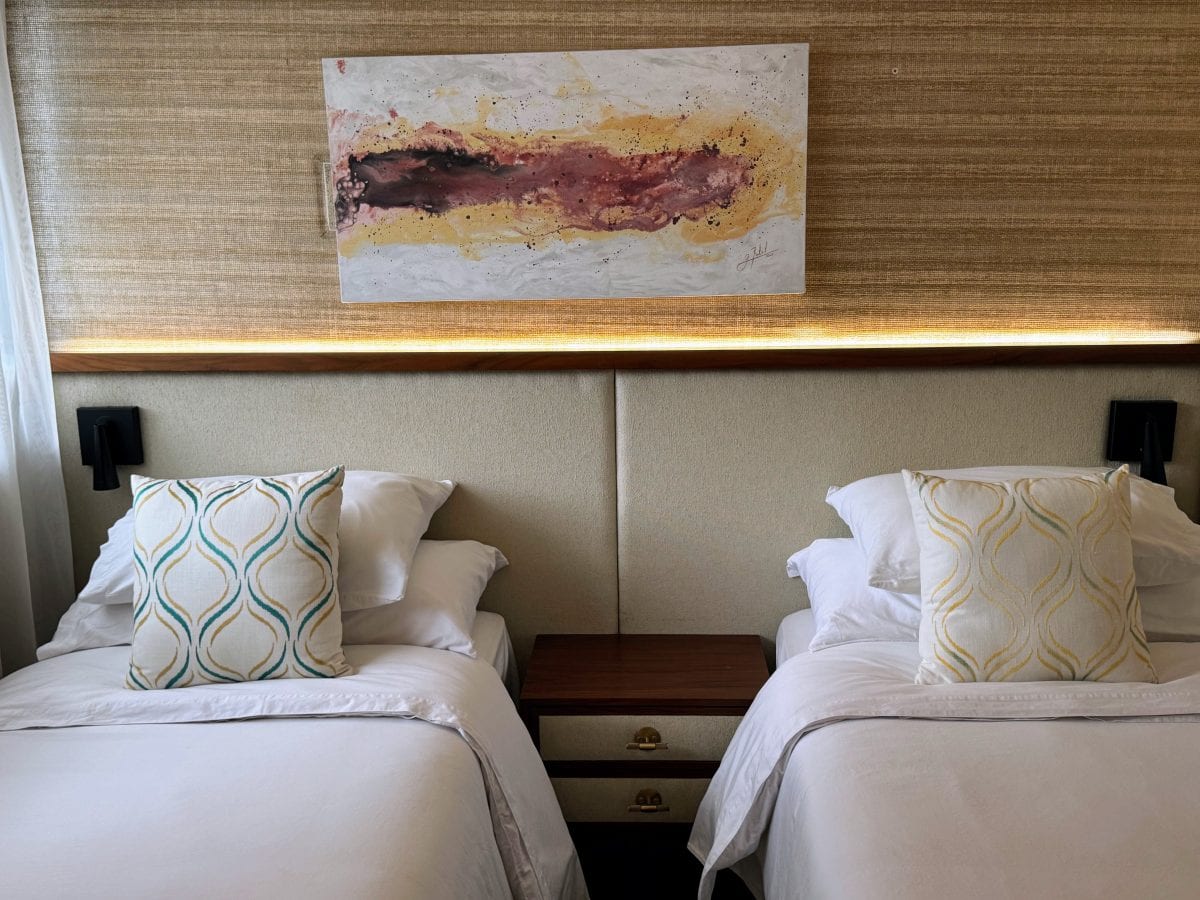 Adventure Cruising with Kontiki Expeditions in Costa Rica 32 Twin beds with decorative pillows and abstract wall art in hotel room.