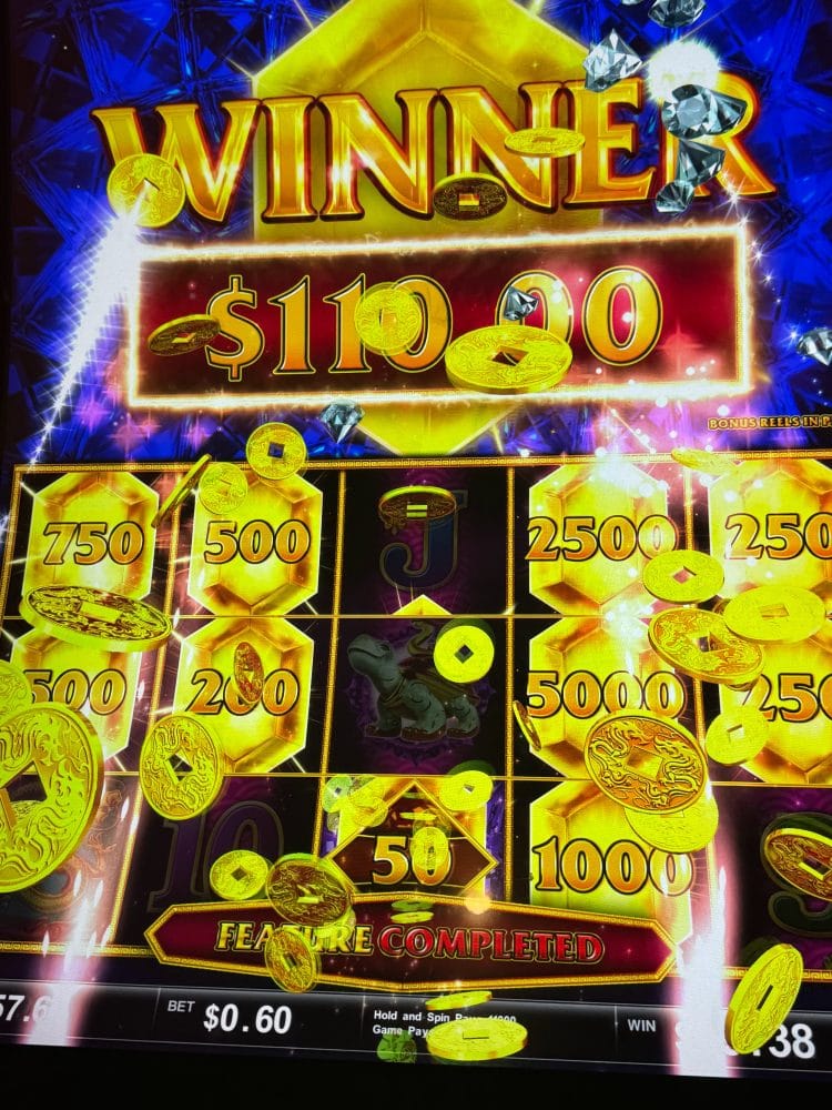 Casino slot machine showing a $1100 win with gold coins and bright lights.