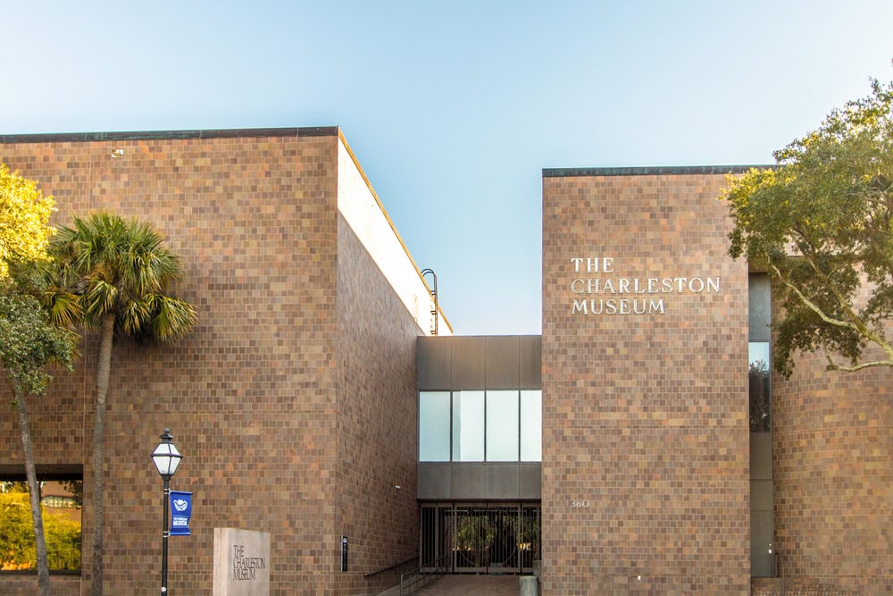 12 Terrific Museums in Charleston to Put on Your To-Visit List 4 The Charleston Museum entrance with brick facade and palm trees.