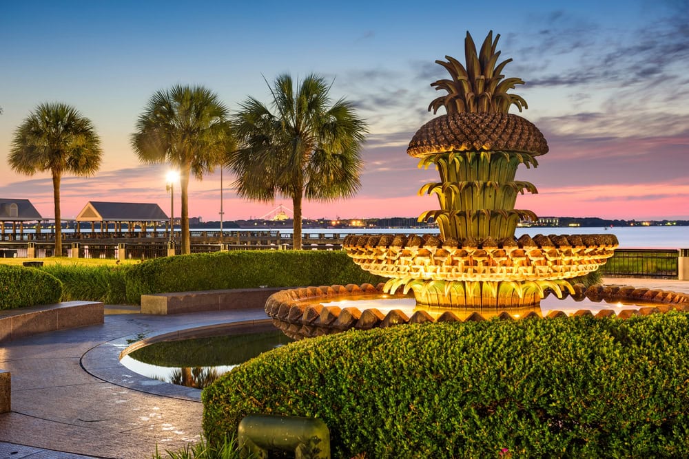 12 Terrific Museums in Charleston to Put on Your To-Visit List 9 Fountain sculpture with palm trees at sunset in Charleston.